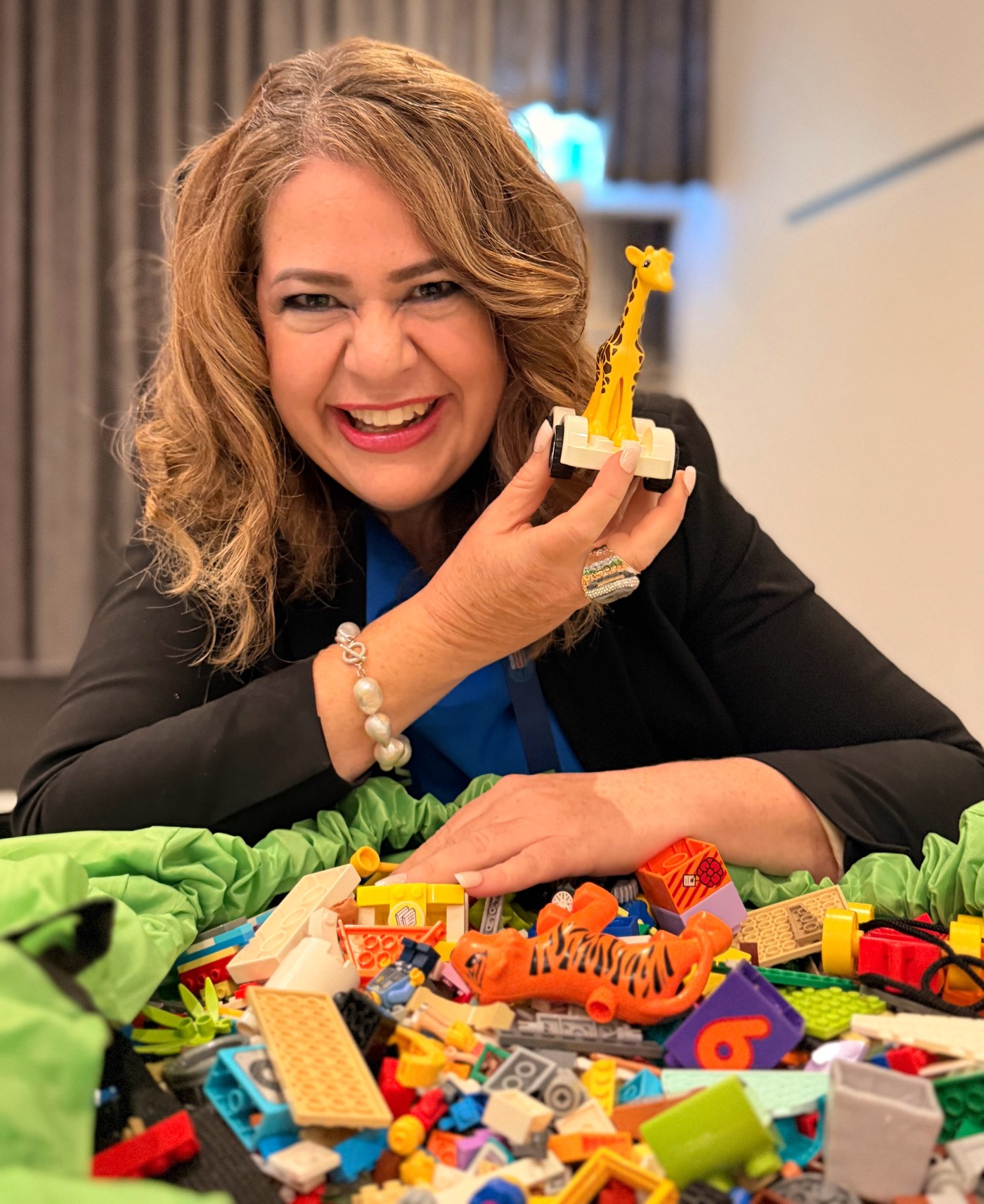 Tanya Hallett smiling in a black jacket with LEGO&reg; bricks
