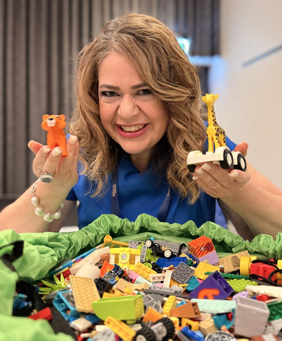 Tanya Hallett smiling while holding LEGO figures during a workshop